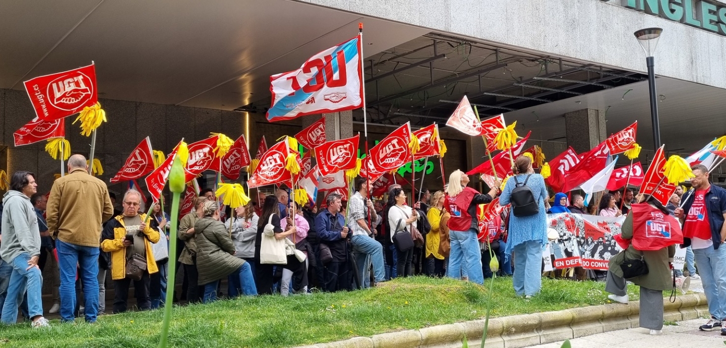 Imaxe do persoal de limpeza diante da porta do Corte Inglés portando bandeiras de UGT.