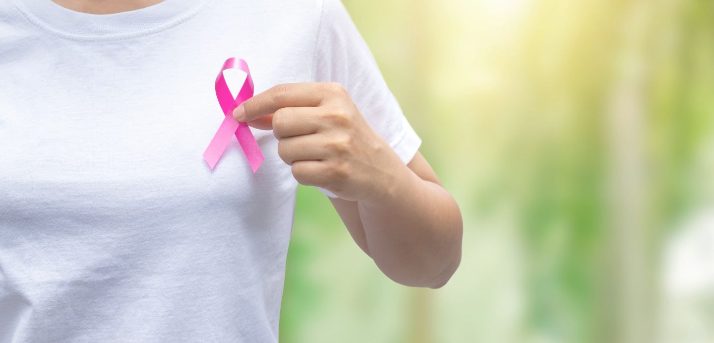 Muller con lazo rosa no peito polo Día mundial contra o cancro de mama.